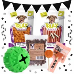Hvalpepakke med Dogman aktivitetsbold, tre poser godbidder og Companion Lollipop med oksekød, vist med Black November-flagguirlande